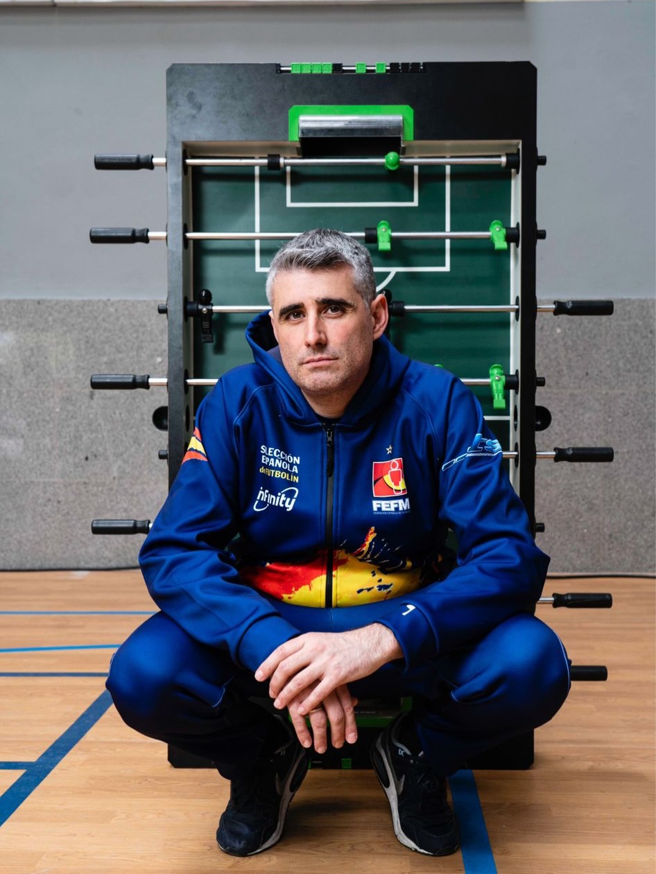 David Gañán con la equipación de la Selección Española de Futbolín, junto a una mesa de futbolín